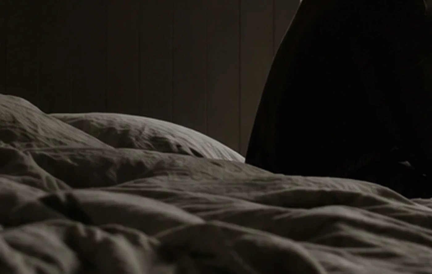 Layered charcoal linen across an unmade bed