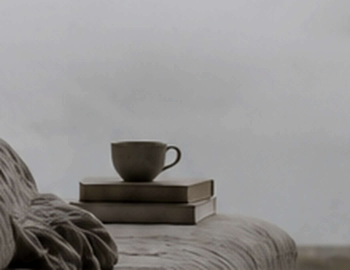 Coffee cup resting beside books in soft morning light